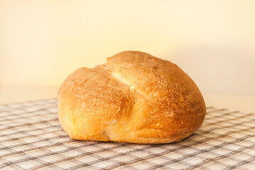 Bread lies on checkered tablecloth in warm soft shades beige background. Sourdough bread. Food concept. Front view