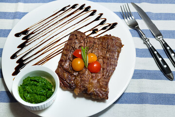 portion of beef steak on a plate with chimichurri sauce and balsamic sauce, top view