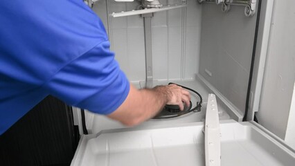 Appliance technician removing a dishwasher strainer basket