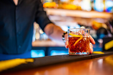 man bartender hand making negroni cocktail. Negroni classic cocktail and gin short drink with sweet vermouth, red bitter liqueur
