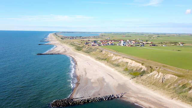 holiday in Denmark, aerial view of the cliff along the North Sea between the famous Bovbjerg Fyr lighthouse and the village Ferring with its white church and the Ferring S&oslash; Fjord in the background