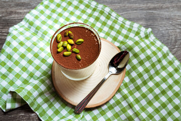 Dessert tiramisu with pistachios sprinkled with cocoa powder. View from slightly above.
