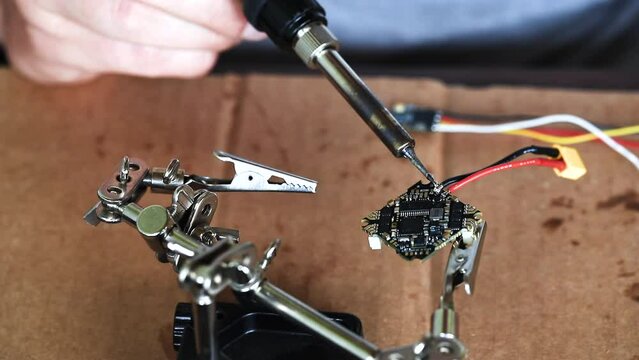 The hand holding the tin, a soldering iron solder the chip in place. Technology Engineering for VR or DIY Concept. . High quality FullHD footage