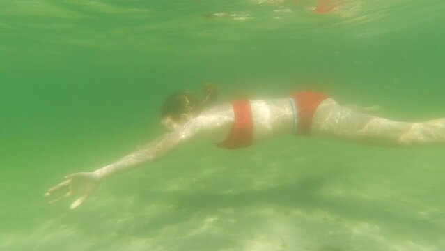 4k slow motion video of a teen girl diving underwater