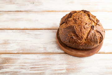 Fresh homemade golden grain bread with wheat and rye on white, side view, copy space.
