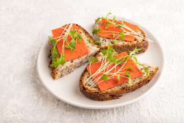 Grain bread sandwiches with red tomato cheese and microgreen on gray, side view, close up.