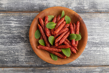 Small smoked sausage with borage microgreen, salt and pepper on gray, top view, close up.