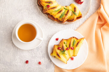 Cheesecake with cup of tea on gray concrete background and orange textile, top view, close up.