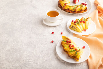 Cheesecake with cup of tea on gray concrete background and orange textile, side view, copy space.