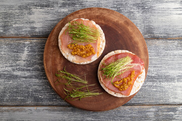 Puffed rice cake sandwiches with jerky salted meat, carrot microgreen on gray, top view, close up.