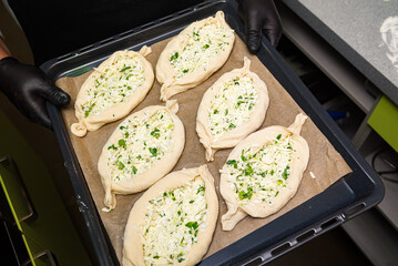 Adjarian khachapuri in the shape of a boat. Six portions on a baking tray as seen from above. Before baking. Ready to be cooked.