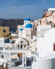 Fototapeta premium View of Oia village in Santorini with traditional white houses and blue domes churches, Greece
