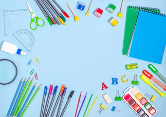 Various supplies for creativity and learning on a blue background with place for text.
