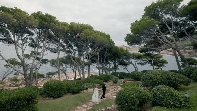 Young Newlywed Couple Is Walking Through Wonderful Park With Amazing Trees.