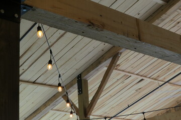 timber frames and ceiling with vintage string lights in barn