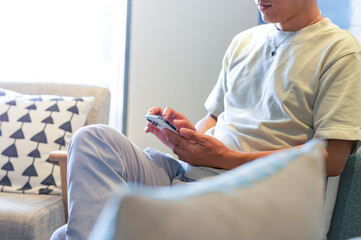 リビングでスマホを操作する男性