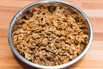Peeled walnuts, large quantities in a metal bowl on the table.