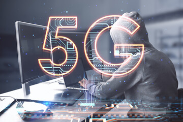 Side view of hacker hands using computers at desktop with creative 5G hologram on blurry office interior background. Speed, internet, hacking, and technology, communication concept. Double exposure.