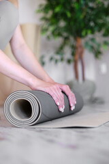 Fototapeta premium Close-up of a woman's hands preparing a mat for yoga or meditation.