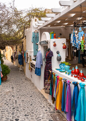 Scenic alley with a shop selling colorful clothes and handicraft products, Oia, Santorini, Greece