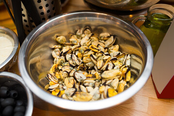 A bowl of raw mussels, a handful ready to cook