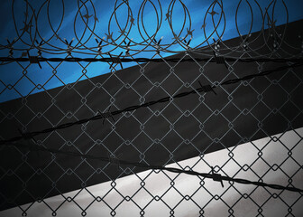 Fototapeta premium Estonia flag behind barbed wire and metal fence
