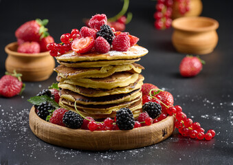 A stack of pancakes with fresh fruits poured with syrup on a black background