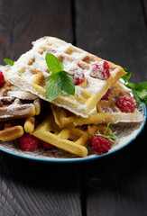 Stack of baked Belgian waffles with ripe red raspberry sprinkled with powdered sugar, breakfast
