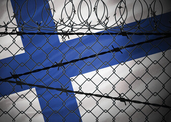 Finland flag behind barbed wire and metal fence