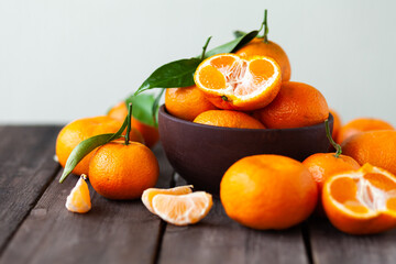Fresh ripe tangerines in a bowl on wooden background. Natural source of vitamin C in winter. Christmas lights.