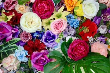 Bright colorful fake flowers and leaves decorating surface. Close up
