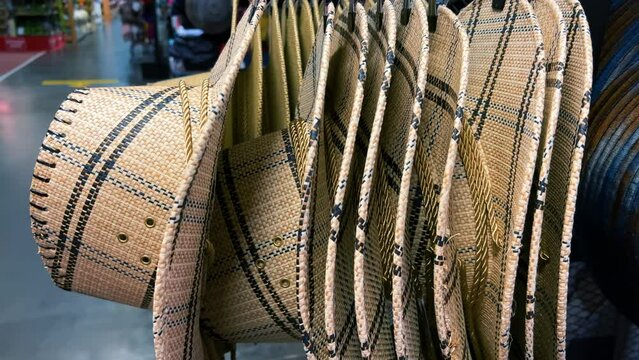 Cowboy wicker hats hang on a stand in a store. Close-up