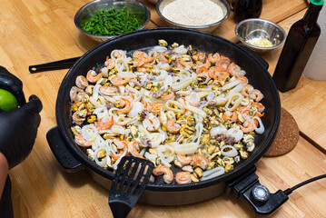 Seafood fried in a paella dish (paella pan). Seafood cocktail. Shrimp, squid, octopus, mussels.