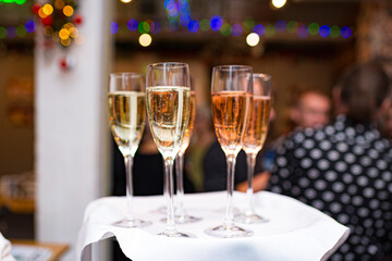 Champagne glasses on the waiter's tray. Serving alcoholic beverages at the party. Welcome drink.