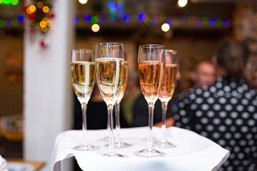 Champagne glasses on the waiter's tray. Serving alcoholic beverages at the party. Welcome drink.
