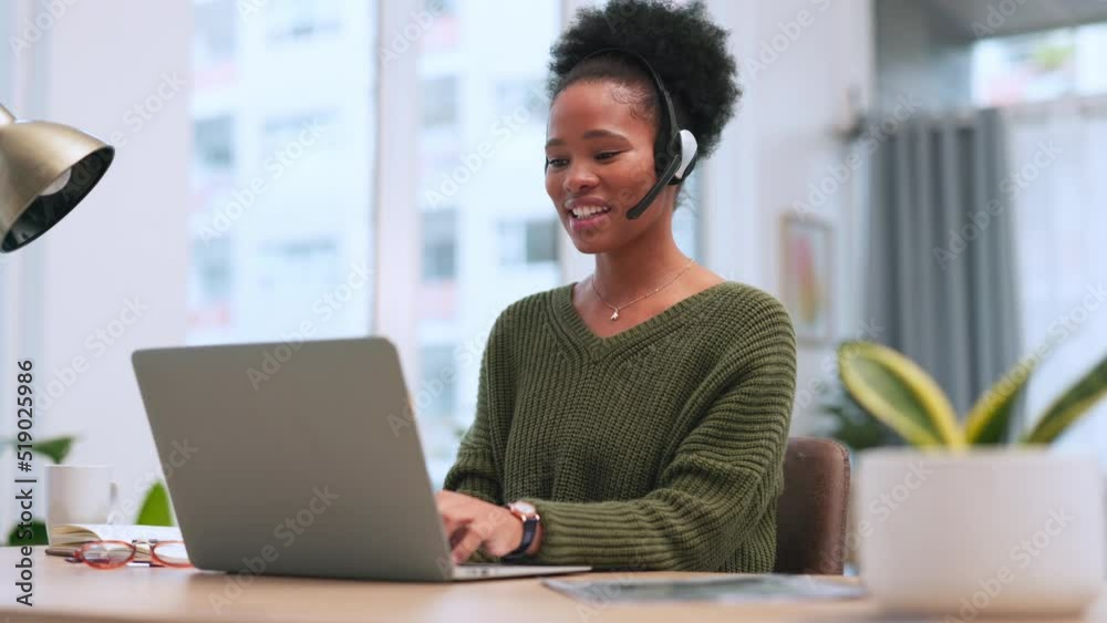 Poster confident black female call centre agent talking on a headset while working on a laptop in an office
