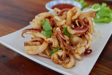 Deep fried crispy squid, calamari on white plate and spicy sauce on side. 