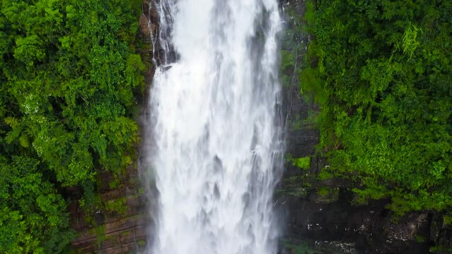 Waterfall among tropical jungle with green plants and trees. Mapalana Falls. Sri Lanka.