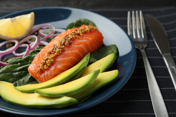 Delicious salmon with spinach and avocado served on fabric, closeup