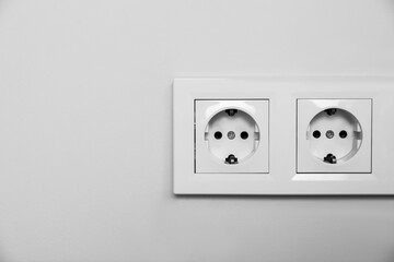 Power sockets on white wall, space for text. Electrical supply