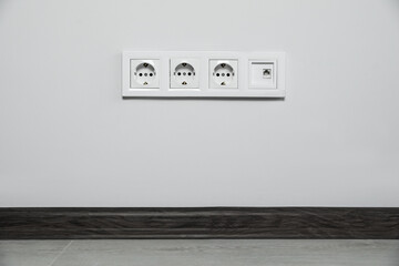 Power sockets on white wall indoors. Electrical supply