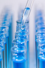 Dripping reagent into test tube with blue liquid on light background, closeup. Laboratory analysis
