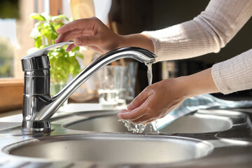 Woman washing hands in kitchen, closeup view