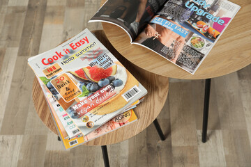 Wooden nesting tables with different magazines indoors, above view