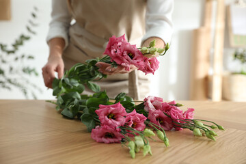 Florist making beautiful bouquet at table in workshop, closeup
