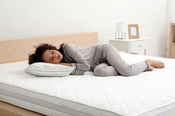 Young African American woman sleeping on bed with comfortable mattress and pillow at home - Powered by Adobe