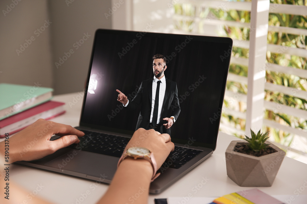 Wall mural woman watching performance of motivational speaker on laptop at white table, closeup