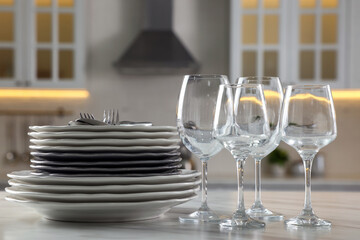 Different clean dishware, cutlery and glasses on white marble table in kitchen