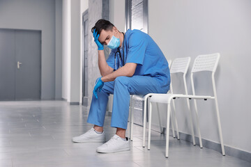 Exhausted doctor sitting on chair in hospital hallway