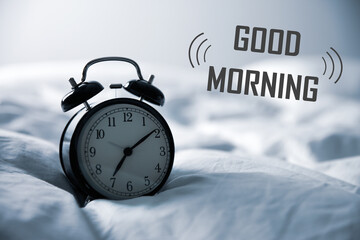 Good Morning! Black alarm clock on bed